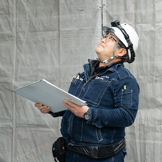 図面を手に持ちながら、建築現場の進捗状況を確認している現場監督の男性