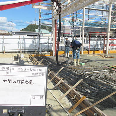 新築の倉庫建設現場で、セメントを基礎の中に流し込んでいく作業員